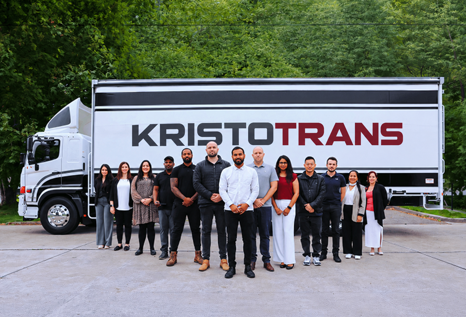 Group of twelve diverse people standing in front of a Kristotrans truck outdoors.